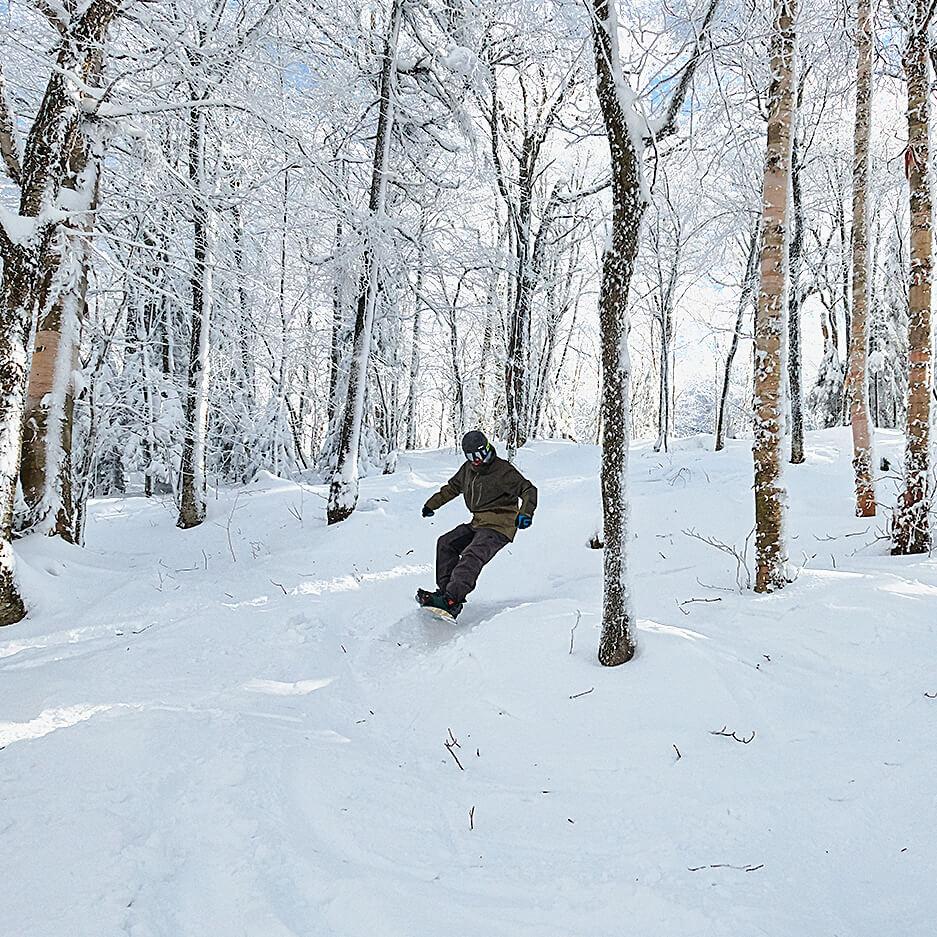 A snowboarder navigates a backwoods trail.