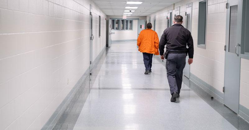 A prisoner is escorted down a hallway at the Southern States Correctional Facility