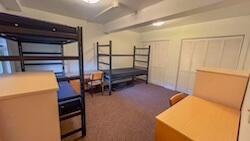 A bedroom with a double bunk and a single bed, closets, desks, and dressers.