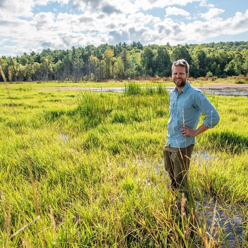 Faculty member Eric Roy standing in a swamp