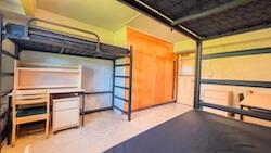 A room with three beds, three desks, a dresser, and two built-in closets. 