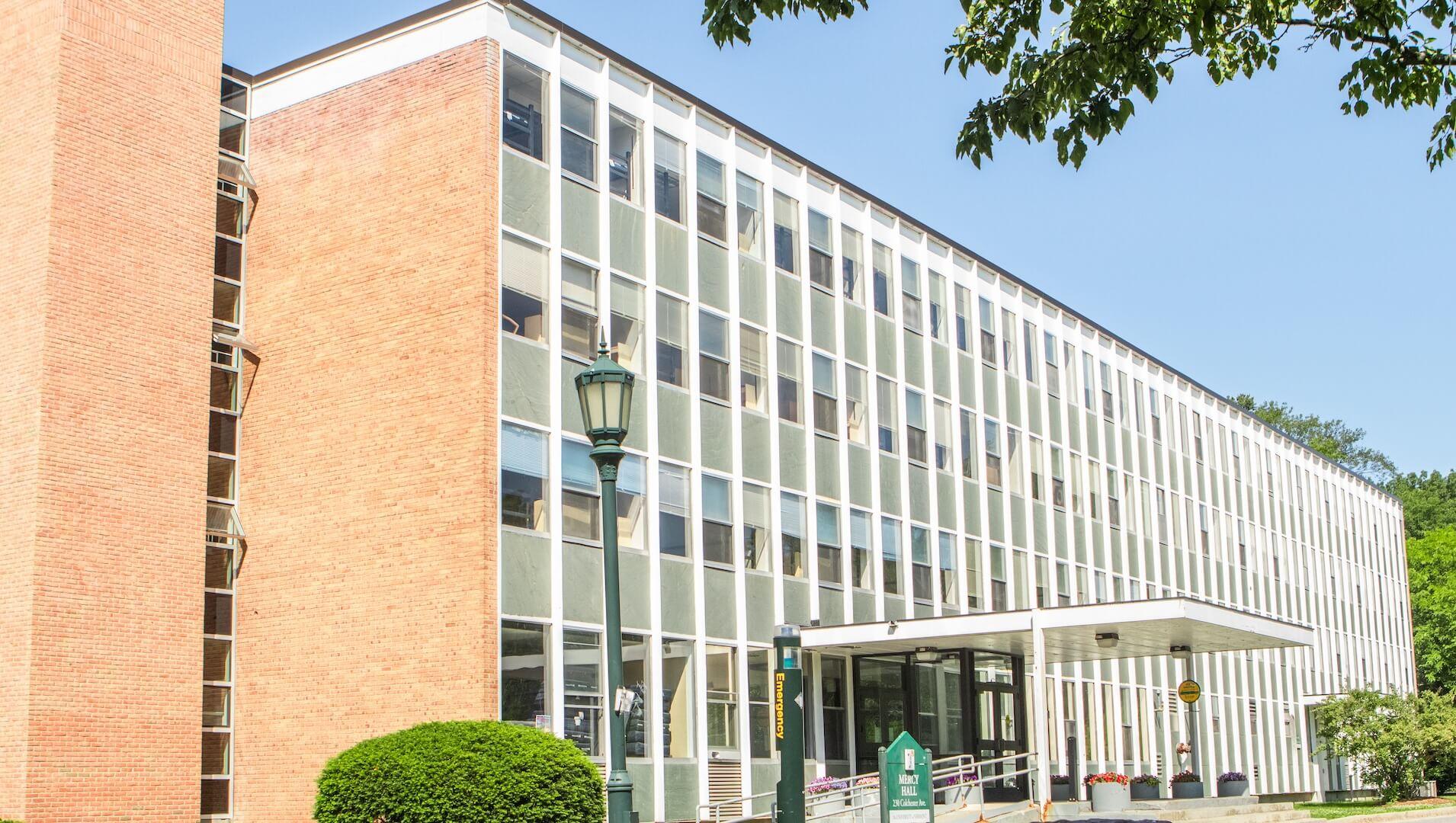 A 4-story brick residence hall with a large wall of windows.