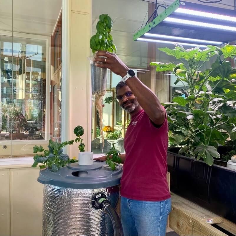 A researcher holding a plant in the air while standing in the Aiken Eco Design space