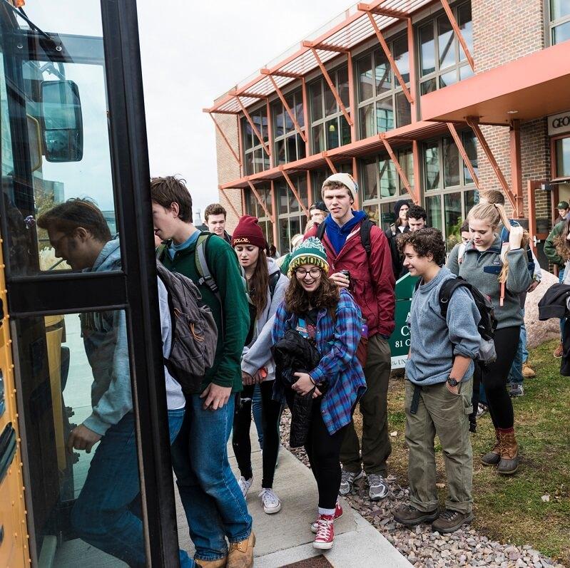 Students getting on a bus outside of the Aiken Center