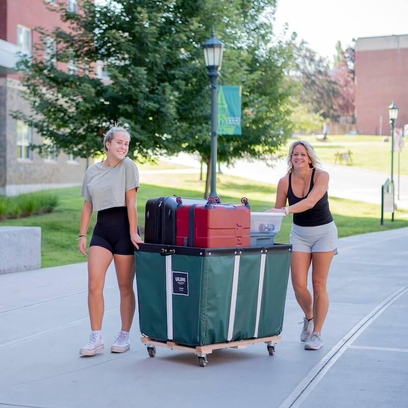 A student and their parent pushing a full move-in cart. 