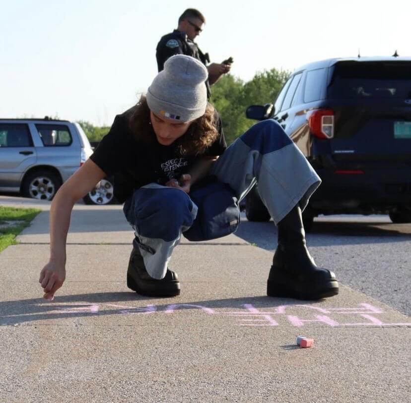 student writes message in chalk
